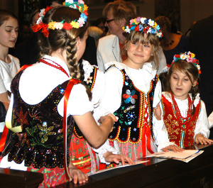 Three little girls dressed up at the catholic migration ethnic