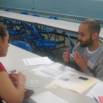 A man and a women discussing and at a table filing out applications