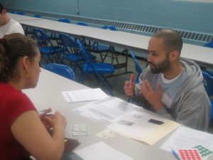 A man and a women discussing and at a table filing out applications