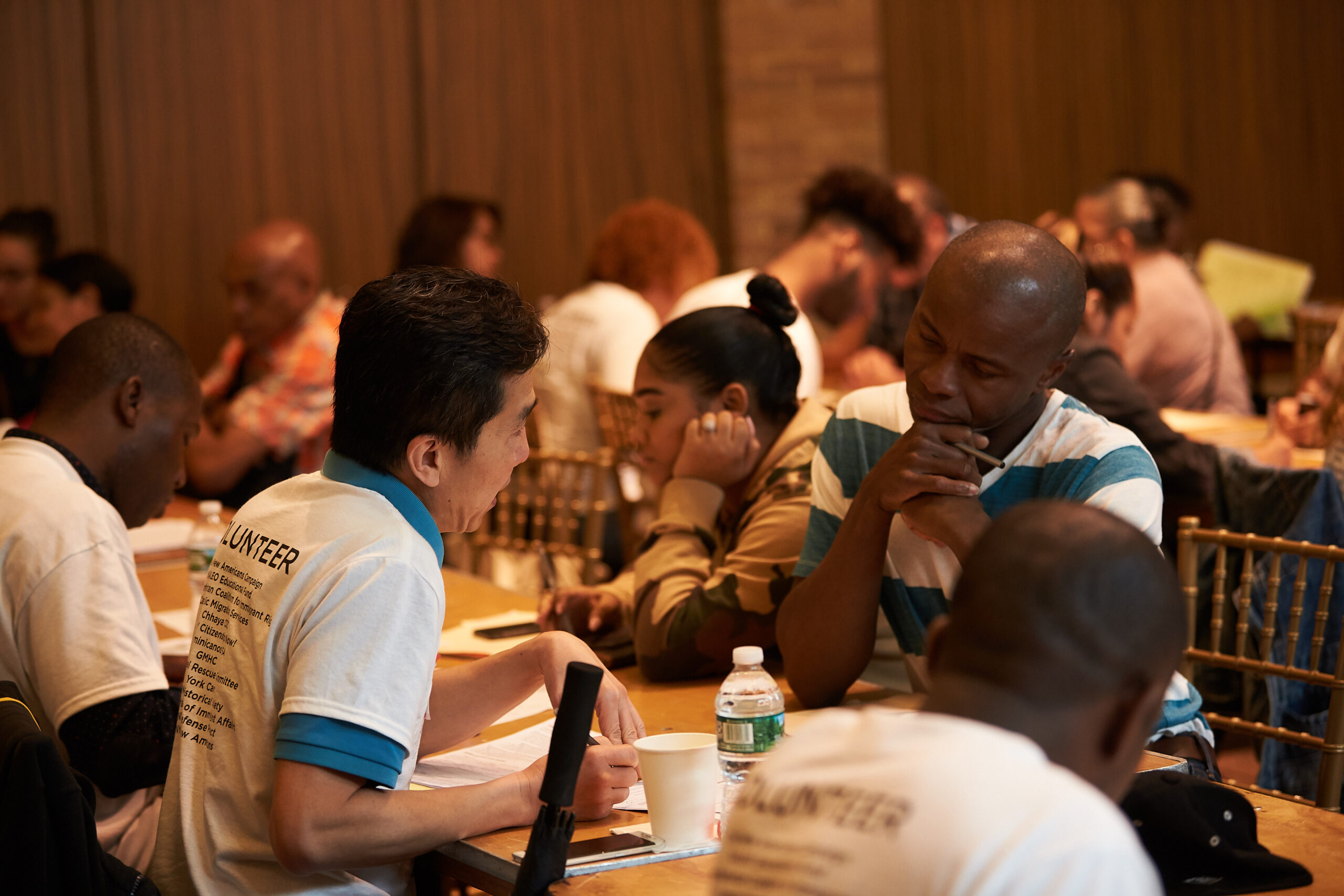 Two Men at a table full of people talking to each other