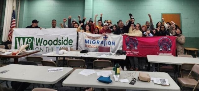 A group of people posed with their fists raised in a community center.